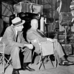 James Stewart talking with director Alfred Hitchcock on the set of “The Man Who Knew Too Much”, 1956