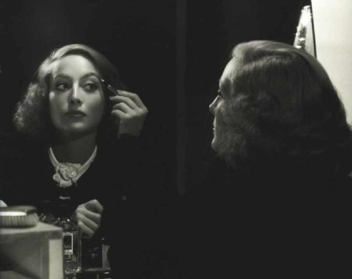Joan-Crawford-applies-max-Factor-makeup-1934b-696x552